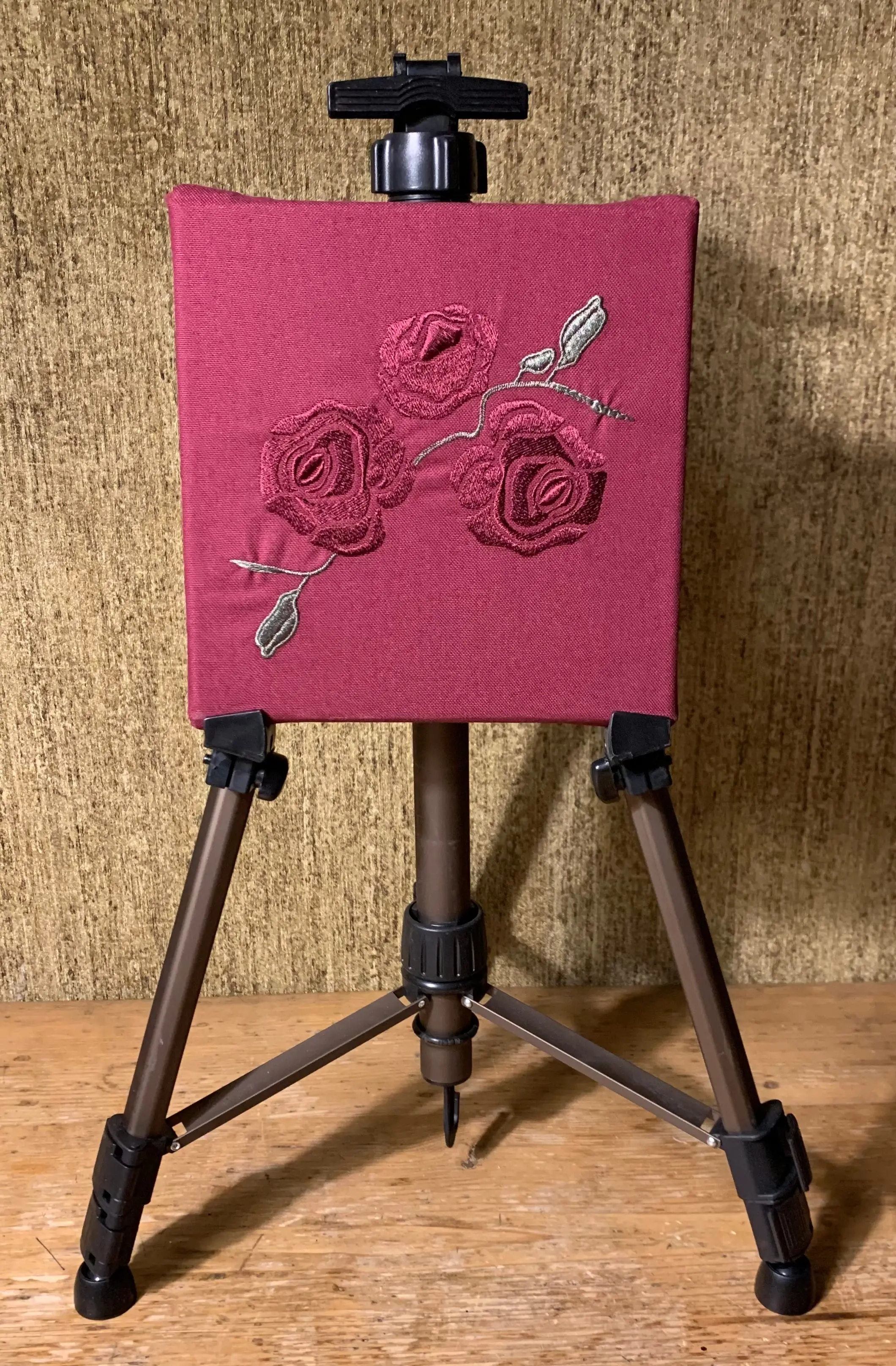 Rote Rose mit grünen Blättern auf rotem Stoff gestickt