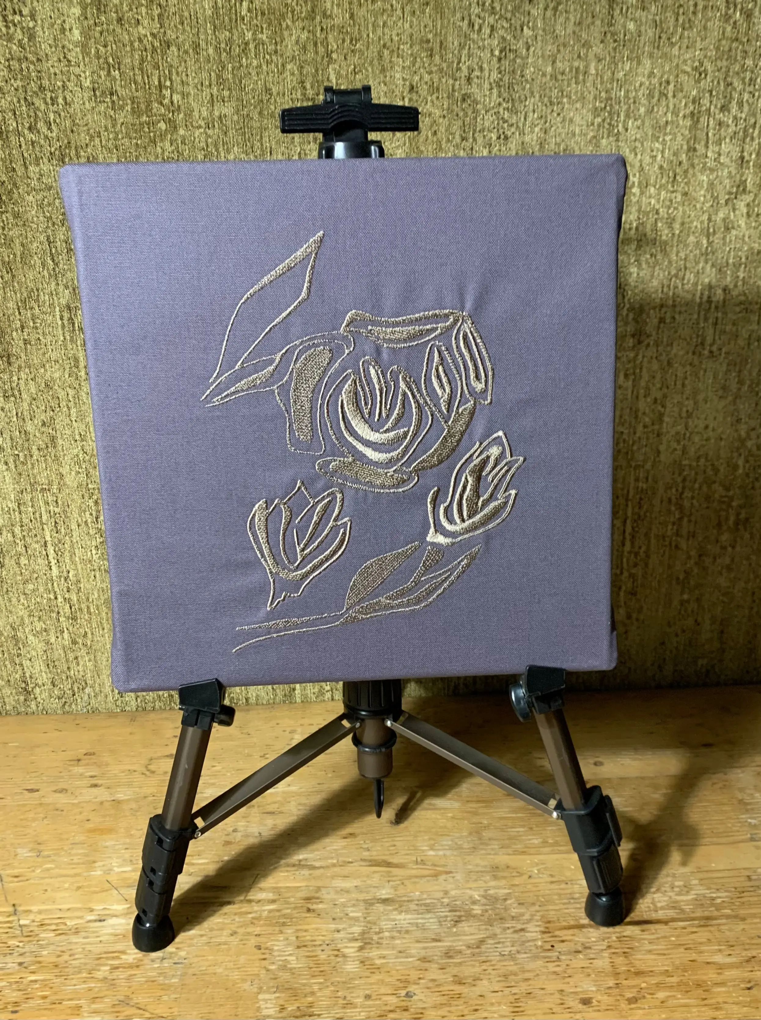 In Gold gestickte Blumen. Der Stoff in grauer Farbe