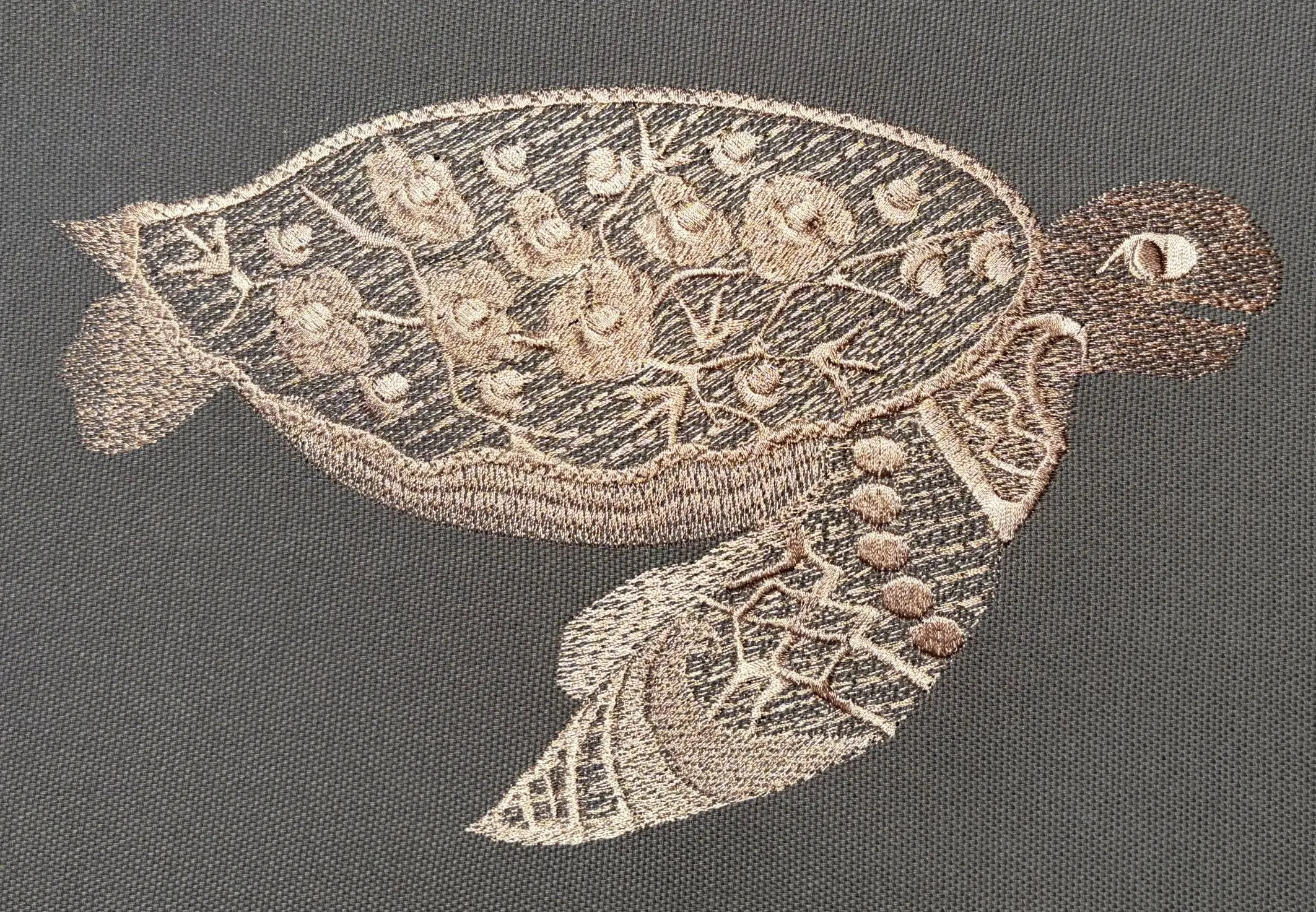 Gestickte Schildkröte mit Blüten auf dem Panzer in Beige auf dunkelgrauem Stoff