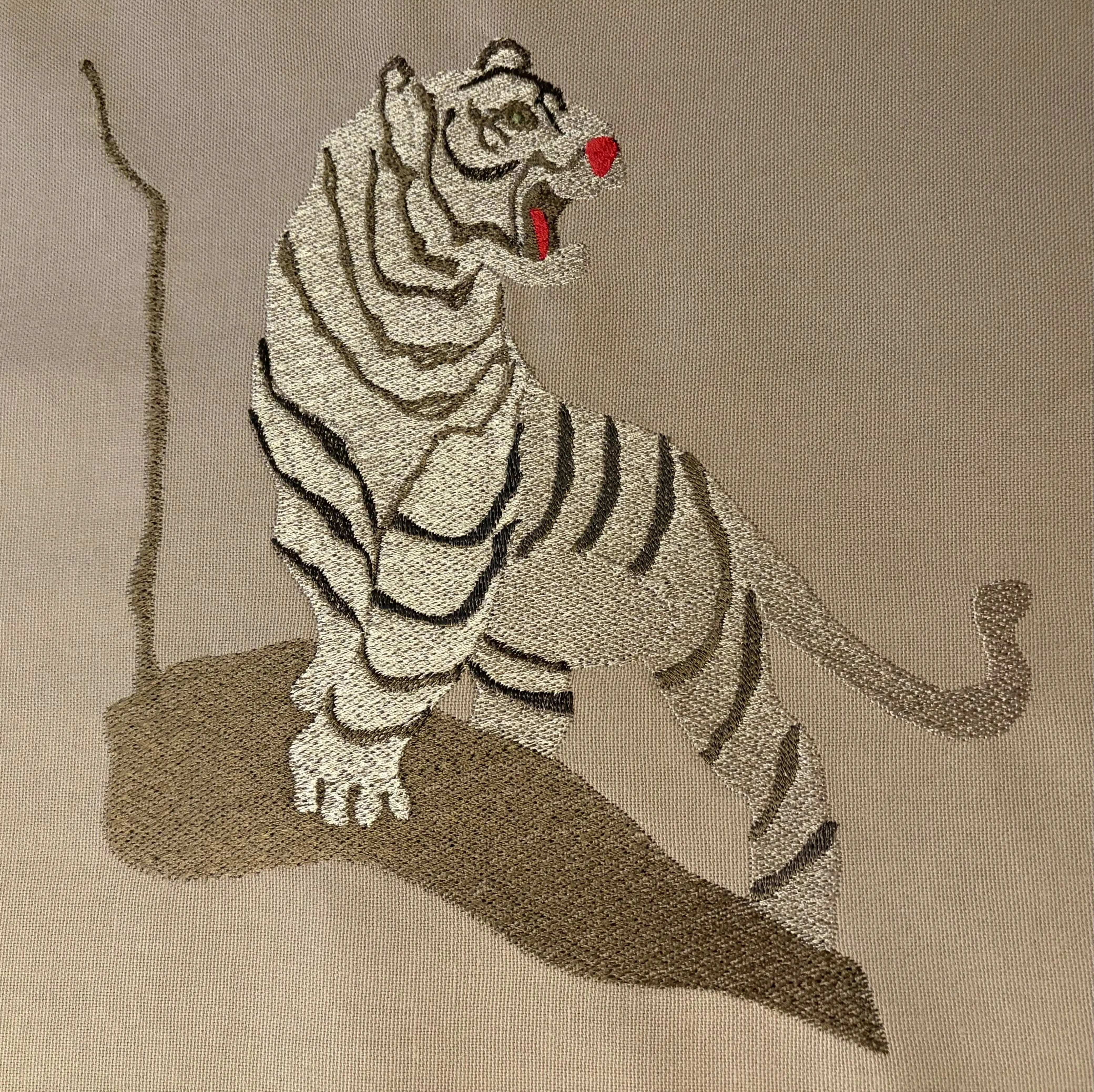 Gestickter Tiger in Silber und Grau mit dunklen Streifen auf beigem Stoff