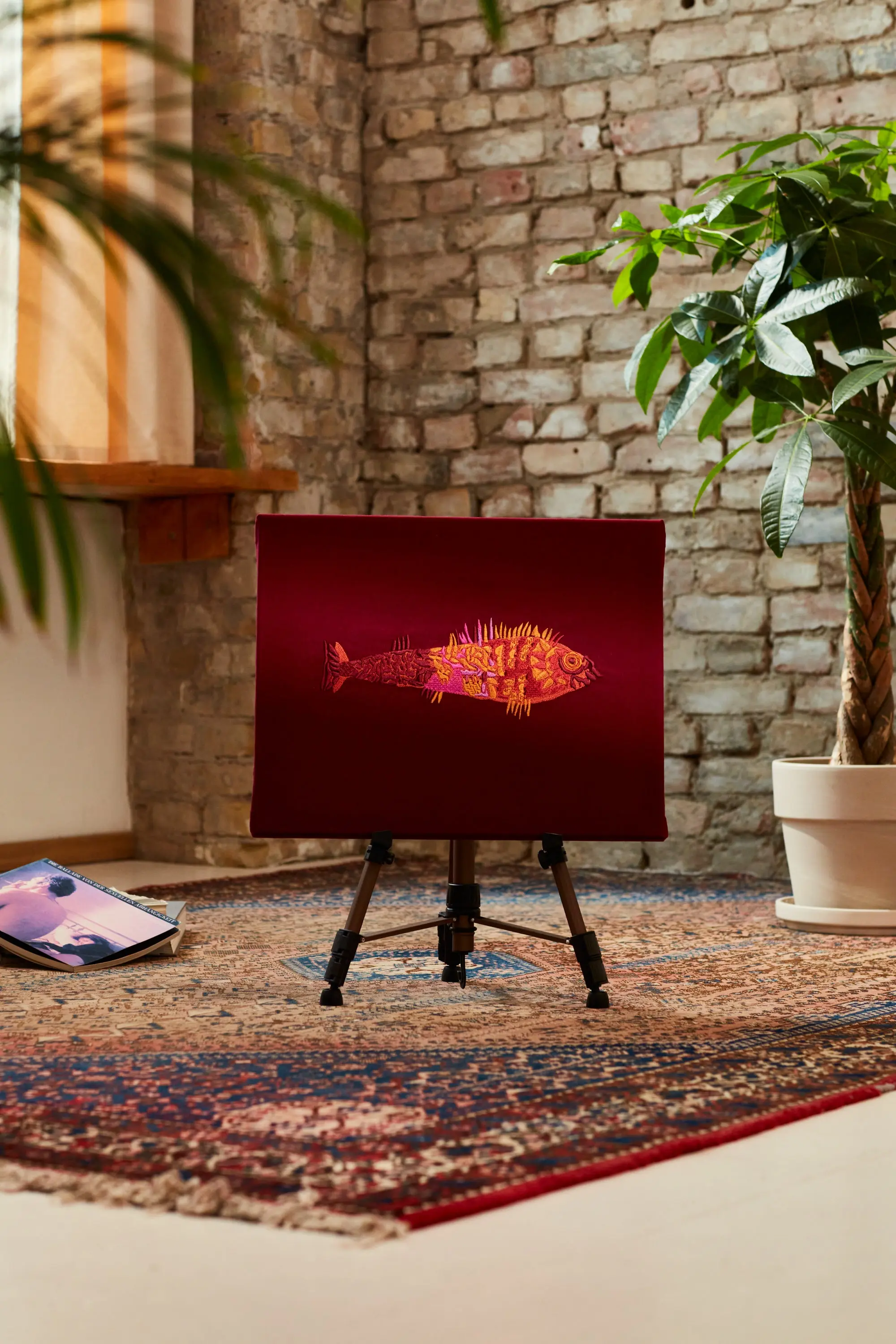 Bunter Fisch in Rot, Orange, Gelb und Rosa auf rotem Stoff