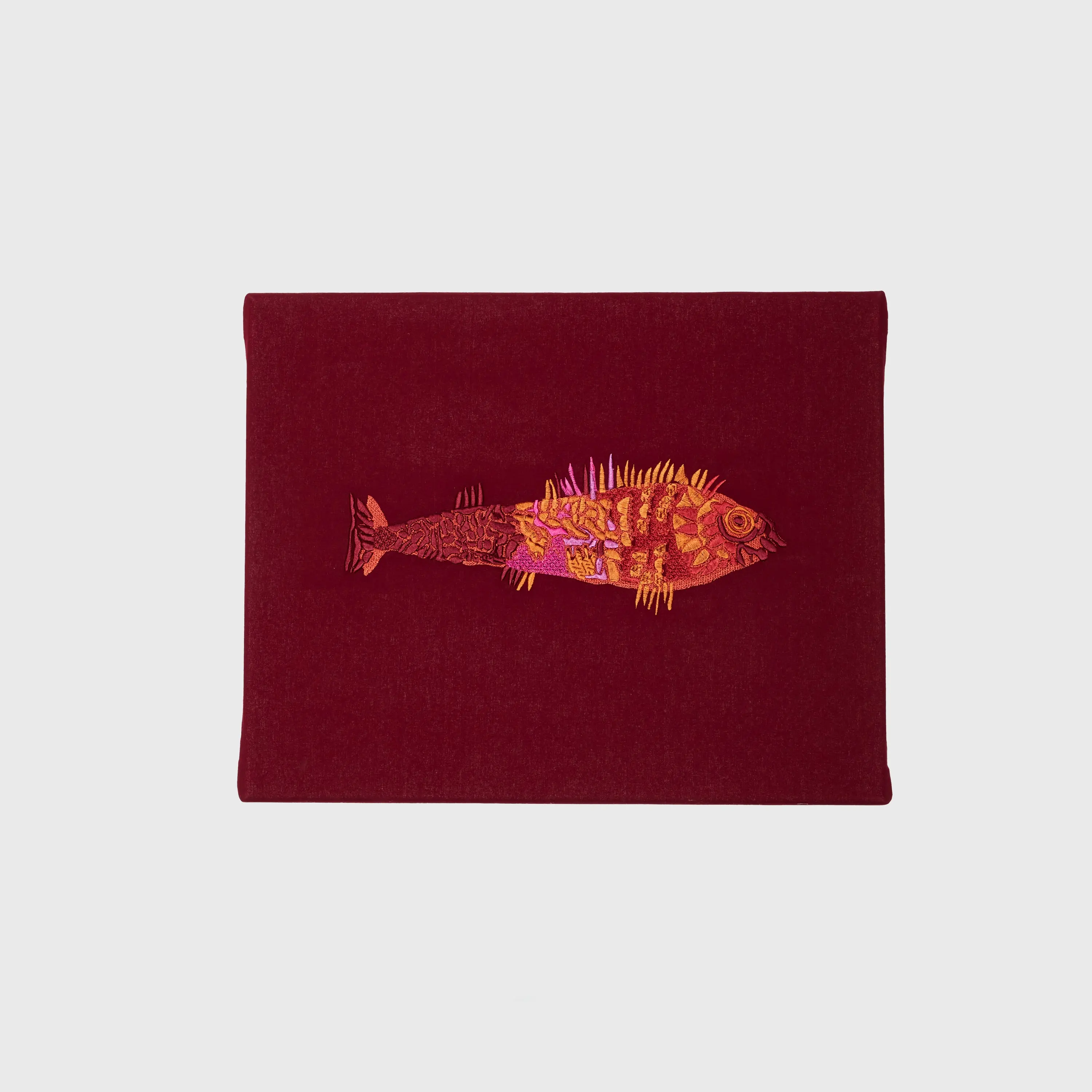 Bunter Fisch in Rot, Orange, Gelb und Rosa auf rotem Stoff
