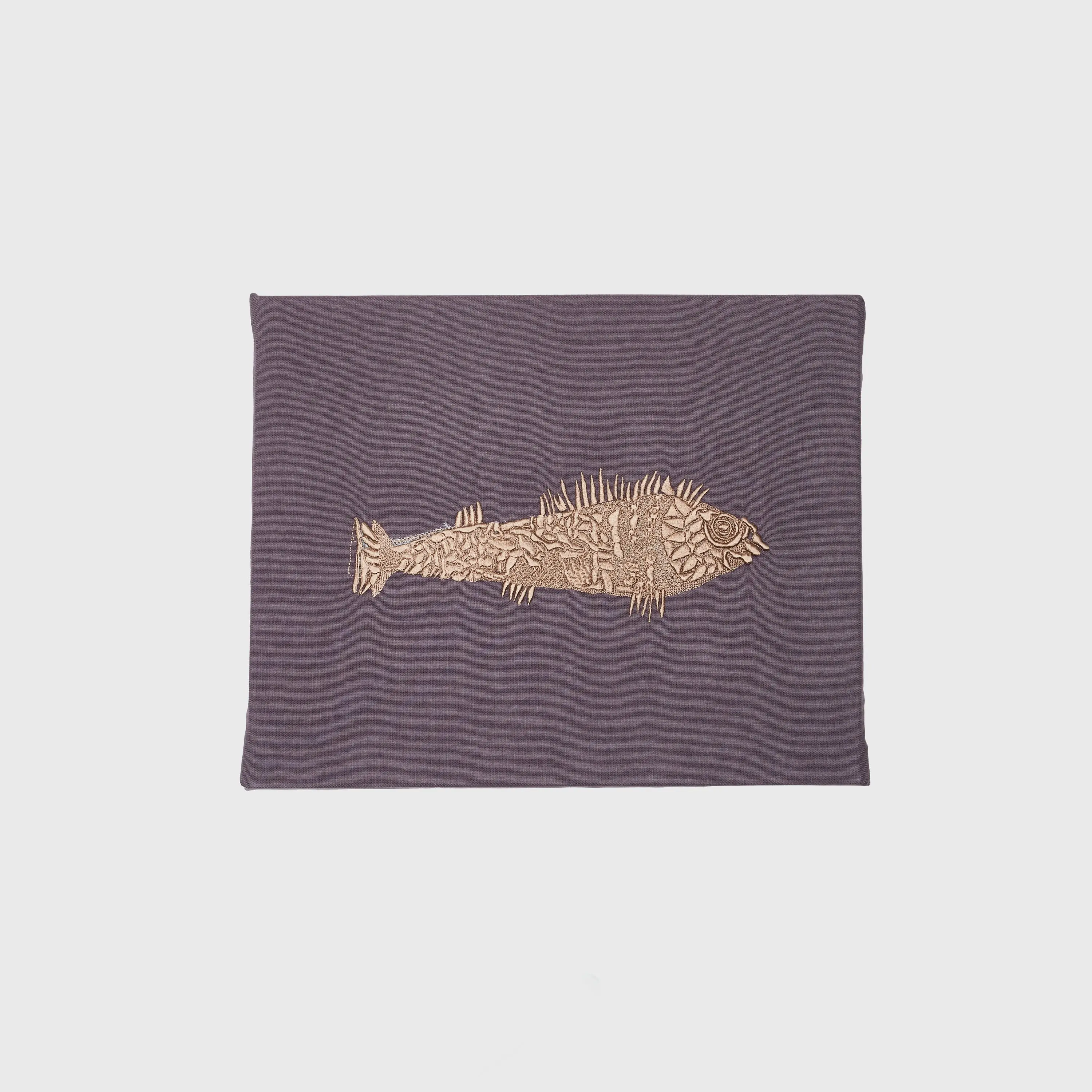 Goldener Fisch auf grauem Stoff